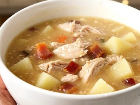 A bowl of creamy bacon ranch chicken chowder with visible pieces of chicken and potato in a rich broth.