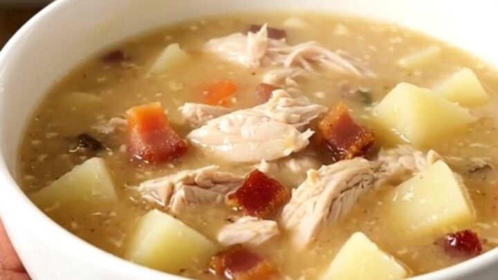 A bowl of creamy bacon ranch chicken chowder with visible pieces of chicken and potato in a rich broth.