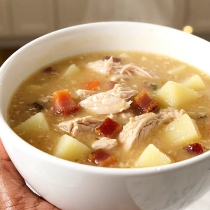A bowl of creamy bacon ranch chicken chowder with visible pieces of chicken and potato in a rich broth.