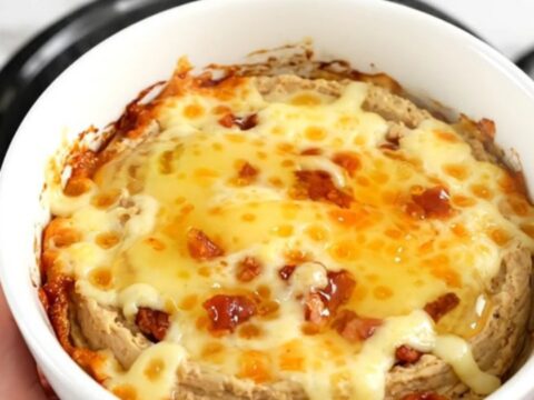 A close-up of the warm honey jalapeno bacon dip in a white bowl with a golden glossy finish.