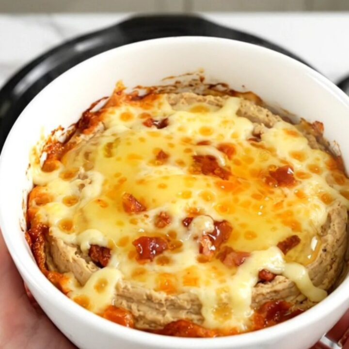 A close-up of the warm honey jalapeno bacon dip in a white bowl with a golden glossy finish.
