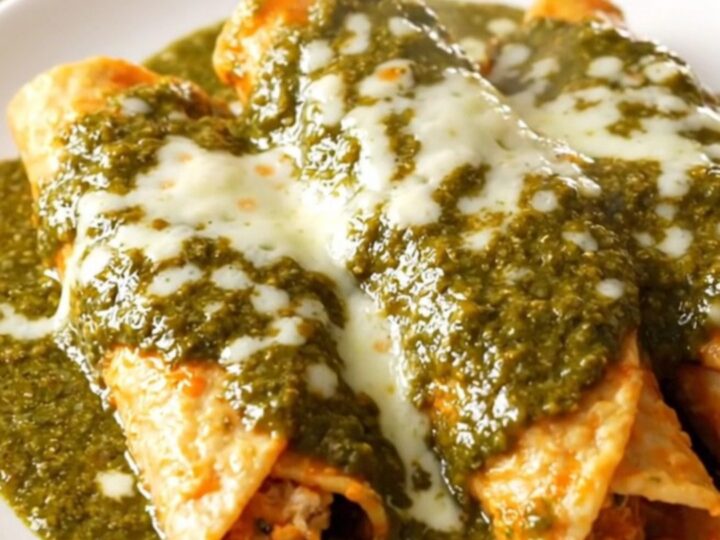 A close-up of creamy shredded chicken with diced poblano peppers in a glossy green sauce.