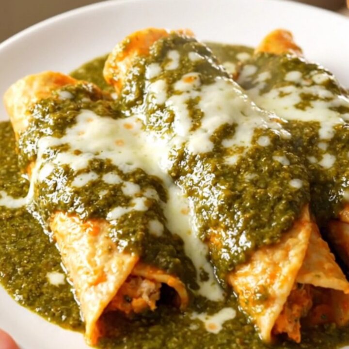 A close-up of creamy shredded chicken with diced poblano peppers in a glossy green sauce.