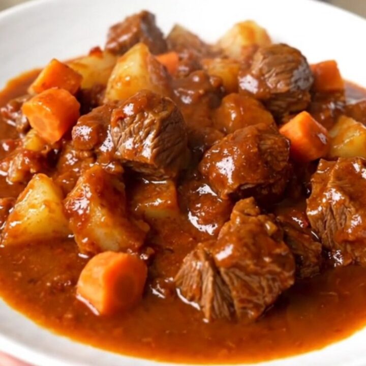 A steaming, glossy portion of slow cooker beef campfire casserole served on a white plate.