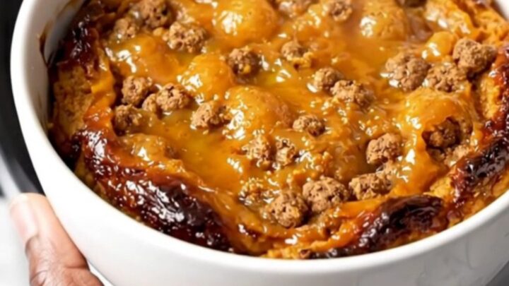 A close-up view of the finished pumpkin gingersnap cobbler served on a plain white plate, showing the steaming