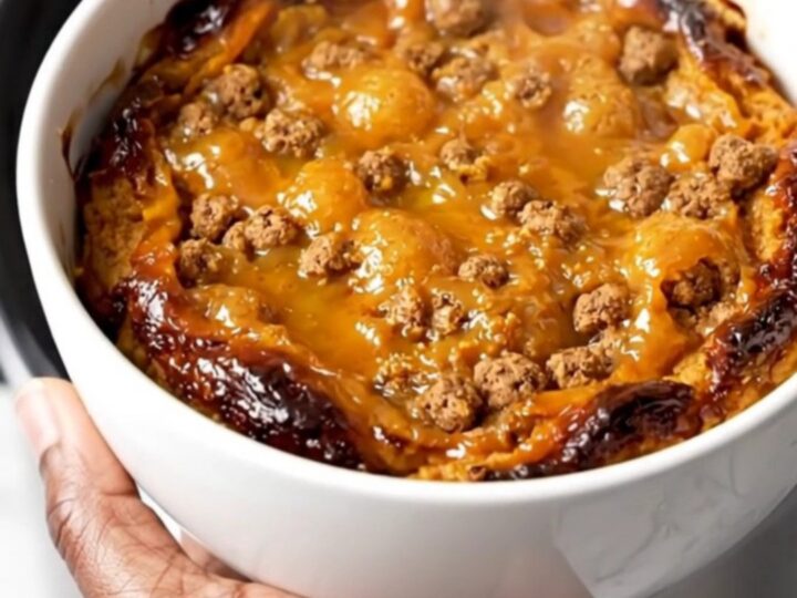 A close-up view of the finished pumpkin gingersnap cobbler served on a plain white plate, showing the steaming