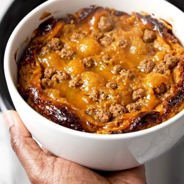 A close-up view of the finished pumpkin gingersnap cobbler served on a plain white plate, showing the steaming
