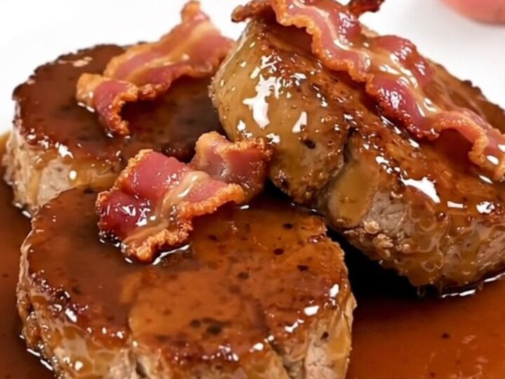 A close-up of glazed maple bacon pork tenderloin medallions on a white plate.