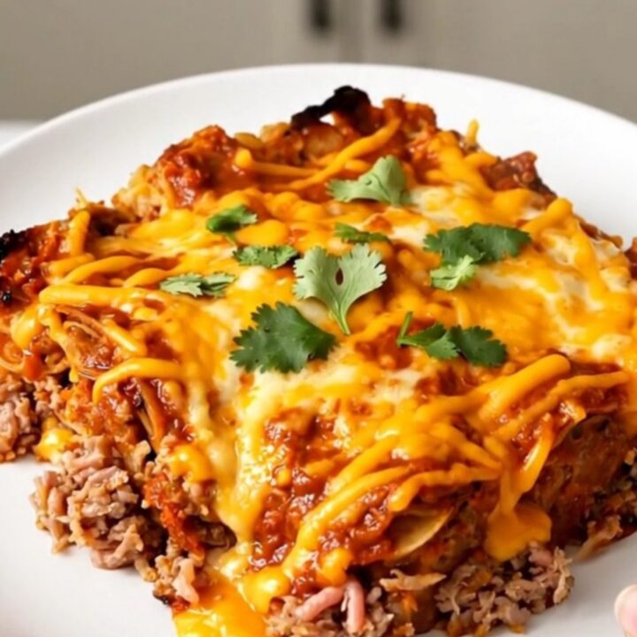 A top-down view of a black slow cooker filled with ground turkey, beans, corn, and red enchilada sauce.