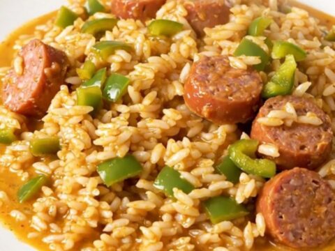 A close-up shot of creamy Cajun smoked sausage and peppers served on a white plate.
