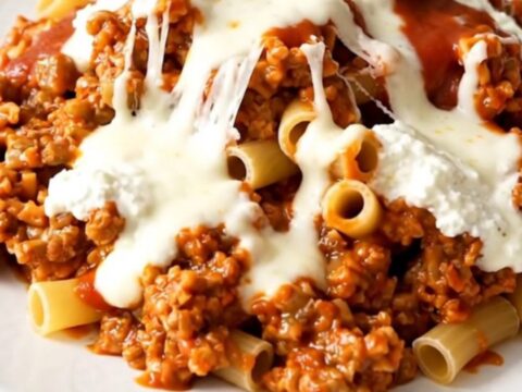 A steaming dish of beef ziti casserole served in a white bowl.