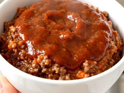 A top-down view of a black slow cooker filled with a savory ground beef and bell pepper dip.