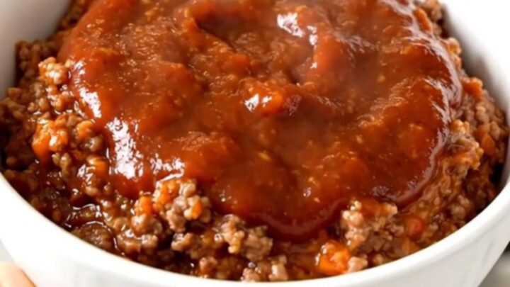 A top-down view of a black slow cooker filled with a savory ground beef and bell pepper dip.