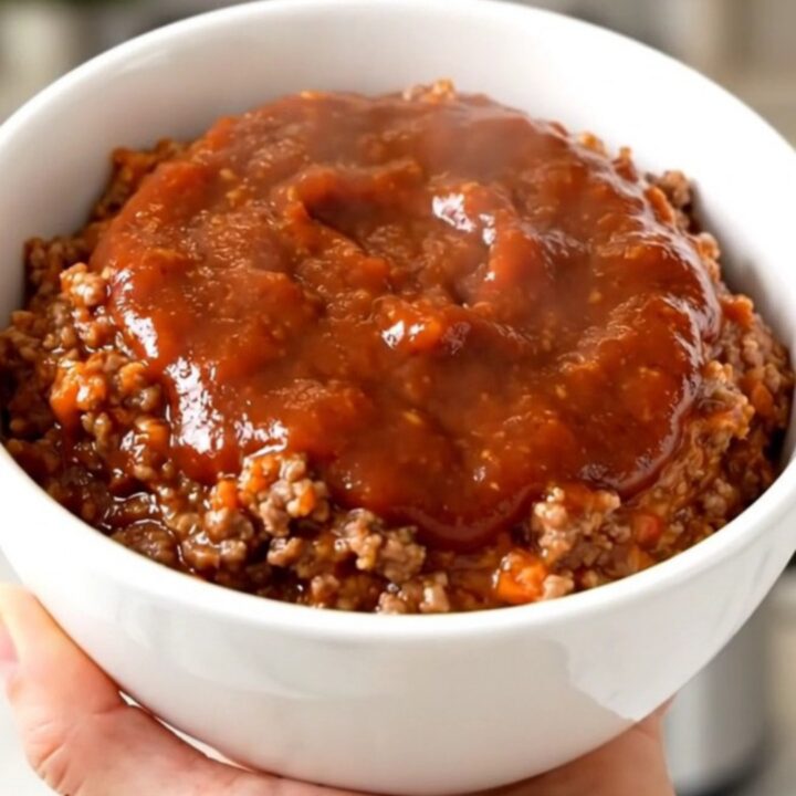 A top-down view of a black slow cooker filled with a savory ground beef and bell pepper dip.