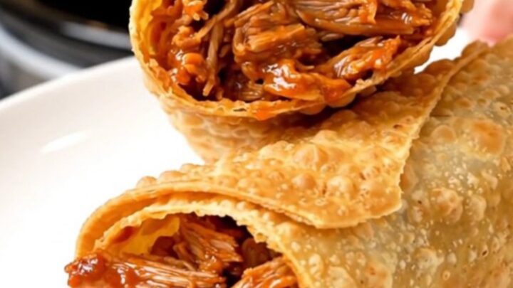 A crispy, golden-brown chimichanga sliced in half on a white plate, showing a steaming, shredded pork filling.
