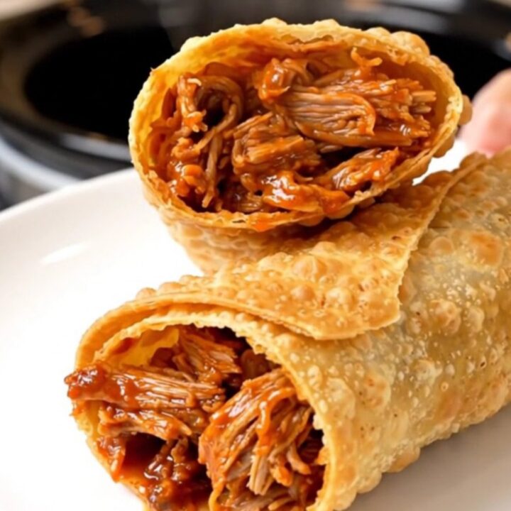 A crispy, golden-brown chimichanga sliced in half on a white plate, showing a steaming, shredded pork filling.