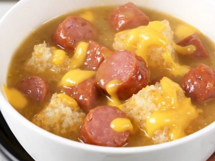 A white ceramic bowl filled with creamy kielbasa and hash brown chowder on a kitchen counter.