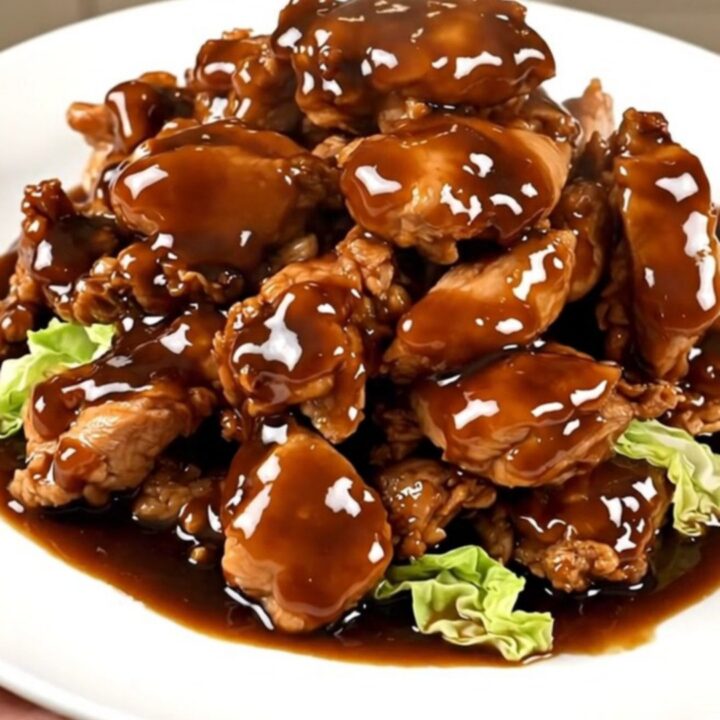 A top-down view of raw chicken, shredded cabbage, and hoisin sauce being layered into a black slow cooker.
