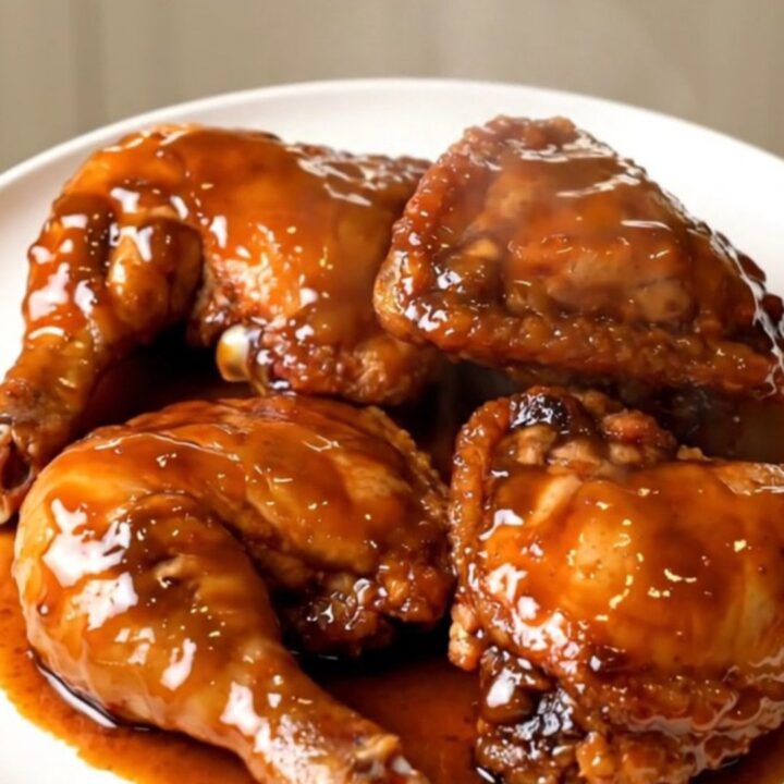 A plate of glistening pumpkin butter glazed chicken thighs served on a white plate.