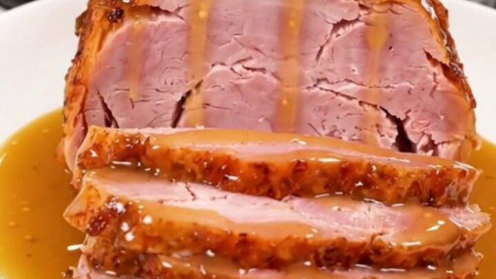 A whole spiral ham in a slow cooker coated with a glossy honey mustard glaze.