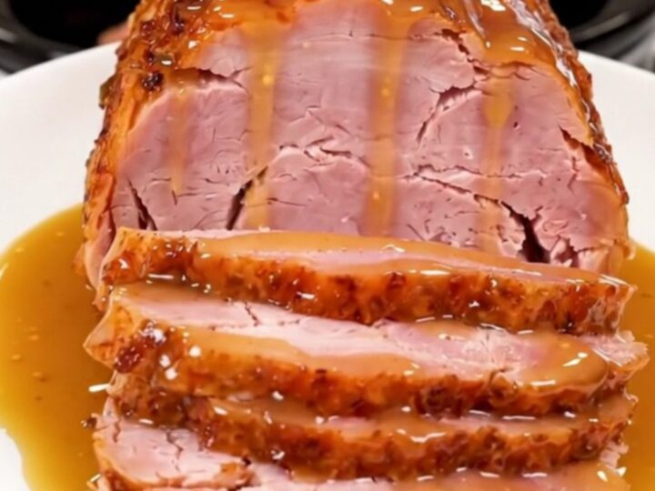 A whole spiral ham in a slow cooker coated with a glossy honey mustard glaze.