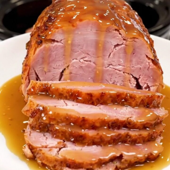 A whole spiral ham in a slow cooker coated with a glossy honey mustard glaze.
