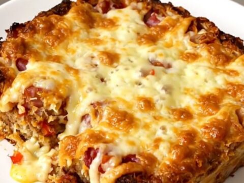 A slow cooker filled with a golden hash brown, sausage, and cheese casserole.