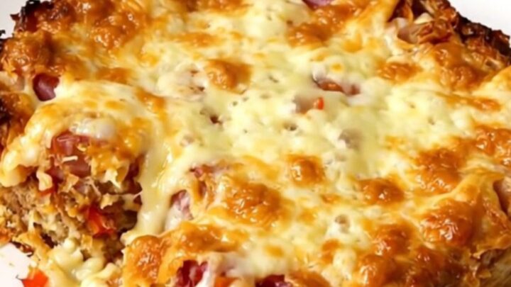 A slow cooker filled with a golden hash brown, sausage, and cheese casserole.