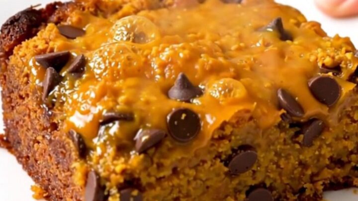 A warm, golden-brown pumpkin chocolate chip dump cake served on a white plate.