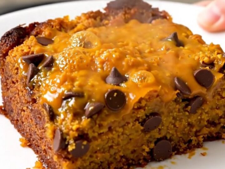 A warm, golden-brown pumpkin chocolate chip dump cake served on a white plate.