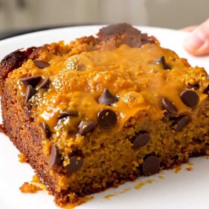 A warm, golden-brown pumpkin chocolate chip dump cake served on a white plate.