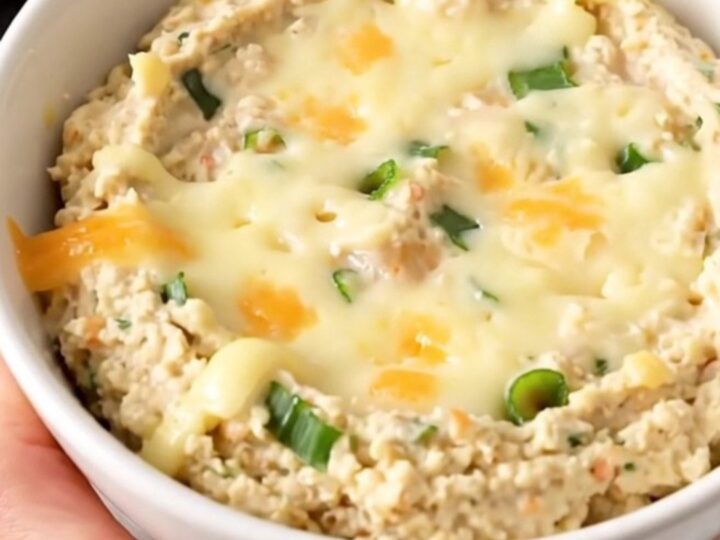 A warm, creamy roasted garlic and parmesan dip in a black slow cooker on a white countertop.