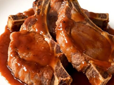 A top-down view of raw pork chops in a slow cooker with soy sauce, garlic, and sweet chili sauce being added.