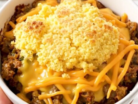 A rustic bowl of Crockpot Green Chile Chicken Tamale with a golden cornbread topping and melted cheese.
