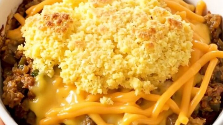A rustic bowl of Crockpot Green Chile Chicken Tamale with a golden cornbread topping and melted cheese.