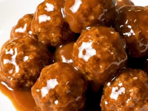 A close-up of glossy, peach barbecue glazed turkey meatballs served on a clean white plate.