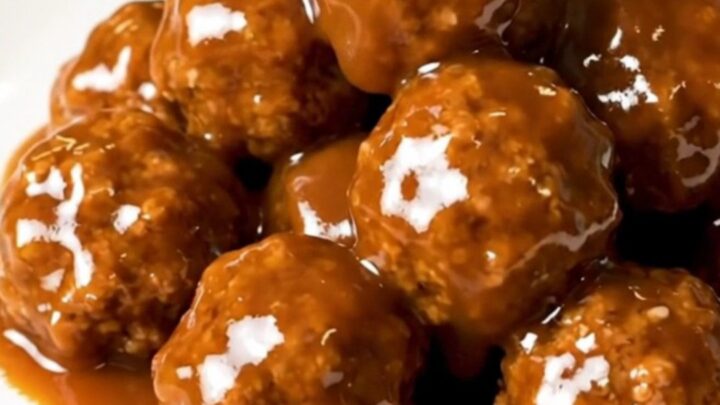 A close-up of glossy, peach barbecue glazed turkey meatballs served on a clean white plate.