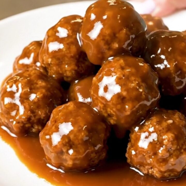 A close-up of glossy, peach barbecue glazed turkey meatballs served on a clean white plate.