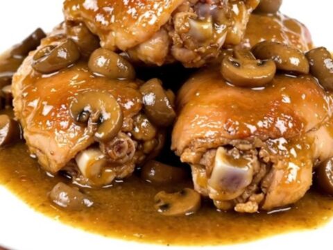 Tender chicken thighs in a glossy mushroom gravy served on a white plate.