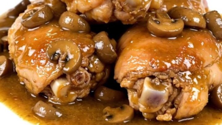 Tender chicken thighs in a glossy mushroom gravy served on a white plate.