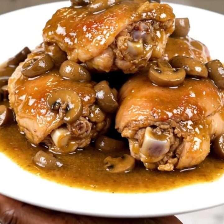 Tender chicken thighs in a glossy mushroom gravy served on a white plate.