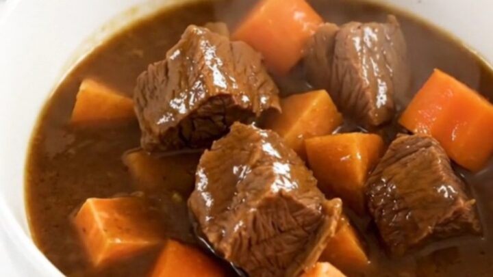 A rustic slow cooker beef stew with tender beef chunks, sweet potatoes, and carrots in a rich apple cider broth.