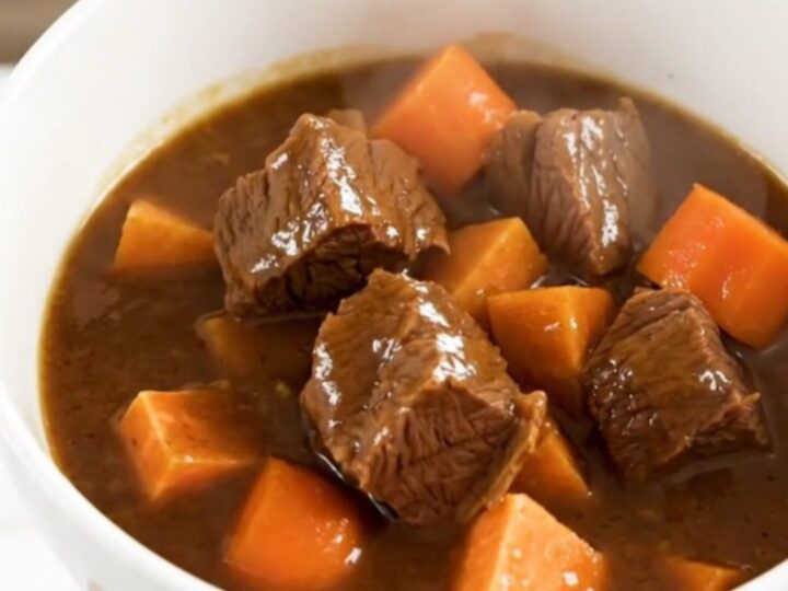 A rustic slow cooker beef stew with tender beef chunks, sweet potatoes, and carrots in a rich apple cider broth.