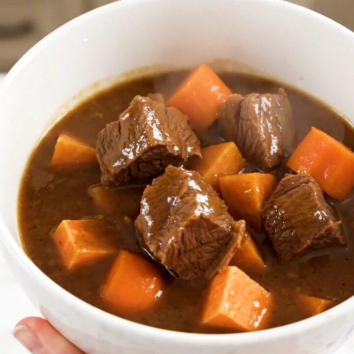 A rustic slow cooker beef stew with tender beef chunks, sweet potatoes, and carrots in a rich apple cider broth.