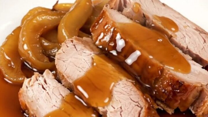 A slow cooker apple maple pork roast served on a white plate with glazed apple slices.