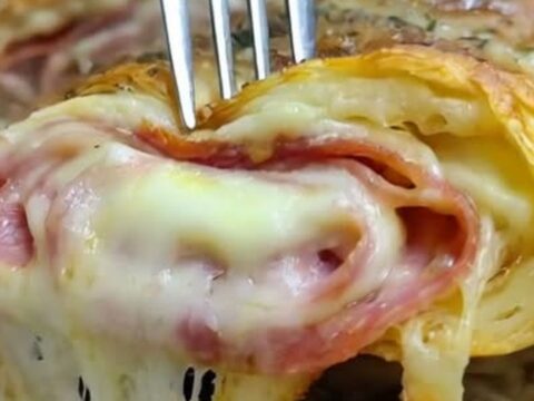 A warm, sliced homemade Italian stromboli on a wooden board, showcasing layers of meats and melted cheese.
