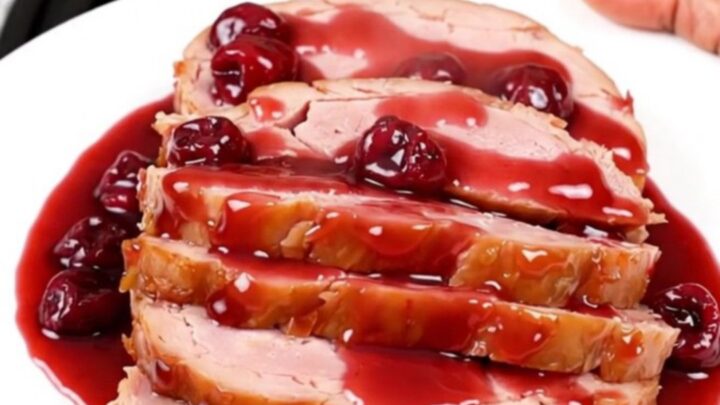 A close-up of a perfectly glazed spiral ham with a rich, glossy cherry sauce in a slow cooker.