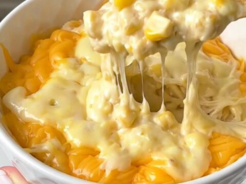 A close-up shot of a bubbly, golden pepper jack corn dip in a white bowl, steaming and ready to eat.