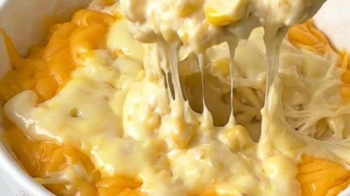A close-up shot of a bubbly, golden pepper jack corn dip in a white bowl, steaming and ready to eat.