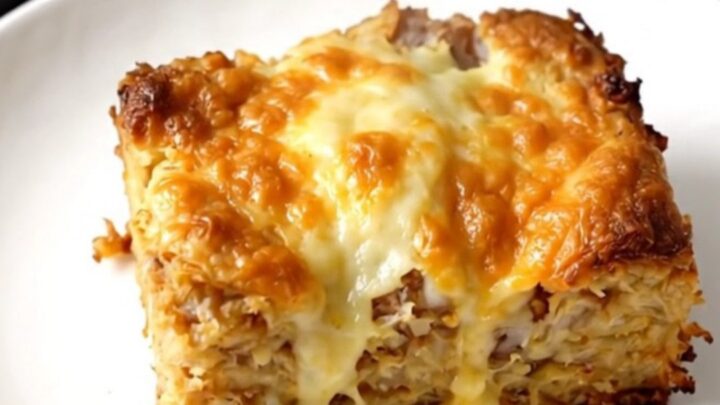 A warm, hearty breakfast casserole served on a white plate with visible hash browns, vegetables, and melted cheese.